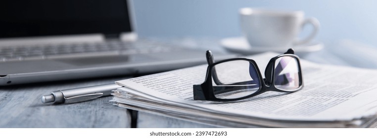 glasses on newspaper and computer on table