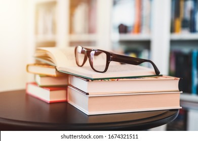 Glasses on stack of books. Library in the background. Books and glasses. - Powered by Shutterstock