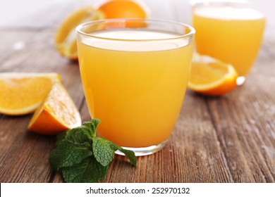 Glasses Of Orange Juice With Oranges On Wooden Table Close Up