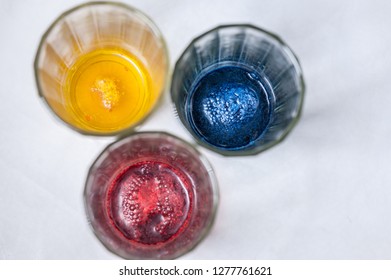 Glasses with paint for Easter eggs. Easter Egg decorating. Close up, soft focus,  top view. Step of painting process. Homemade.