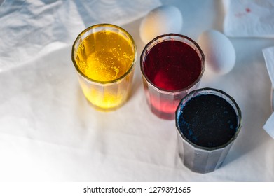 Glasses with paint for Easter eggs. Easter Egg decorating. Close up, soft focus,  top view. Step of painting process. Homemade.