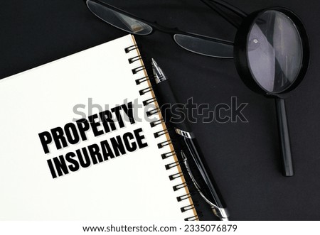 glasses, a pen, a magnifying glass and a book with the word Property Insurance. insurance coverage concept