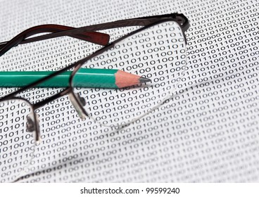 glasses and  pencil on the background of a binary code