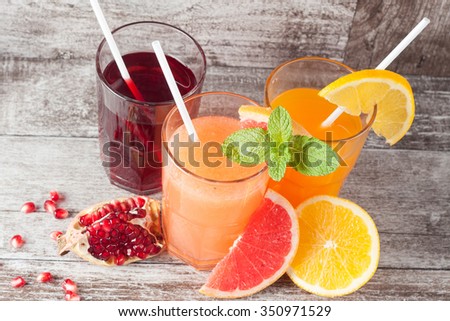 Glasses of pomegranate, grapefruit, orange juice on wooden background. Refreshments and summer drinks. 