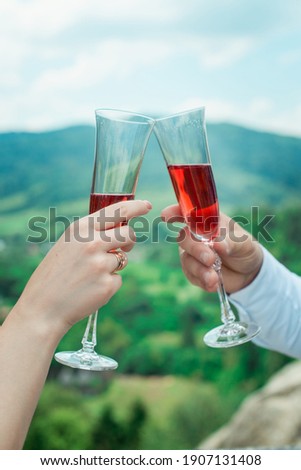 Glasses with red champagne drink in bride and groom hands. Happy newlyweds drinking. Loving couple created new family.