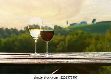 Glasses of red and white wine a wooden table outdoor with landscape background. Wine tasting concept. Copy space. Place for text or message.