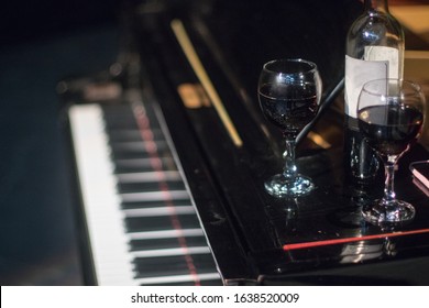 Glasses of red wine and a bottle on a piano on a stage. Red vine.  - Shutterstock ID 1638520009