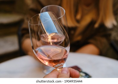 A glasses of rose wine in the hands of a girl and man who relaxing on restaurant terrace. Summer holiday. Celebrate and enjoy moment. Alcoholic drink tasting. Romantic evening aperitif - Powered by Shutterstock