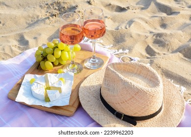 Glasses with rose wine and snacks for beach picnic on sand outdoors - Powered by Shutterstock