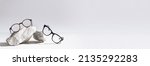 Glasses sale banner. Optic store sale-out offer. Trendy glasses in plastic frame on stones on a light background. Copy space for text. For banner, web line. Optic store discount