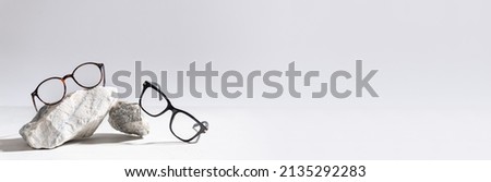 Glasses sale banner. Optic store sale-out offer. Trendy glasses in plastic frame on stones on a light background. Copy space for text. For banner, web line. Optic store discount