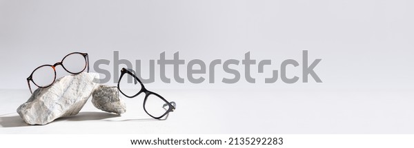 Glasses sale\
banner. Optic store sale-out offer. Trendy glasses in plastic frame\
on stones on a light background. Copy space for text. For banner,\
web line. Optic store\
discount
