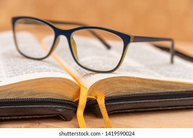 Glasses For Sight Lie On The Bible, The Bible In Leather Black Cover With Tabs Lies On The Table.