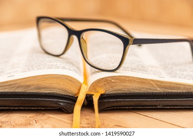 Glasses For Sight Lie On The Bible, The Bible In Leather Black Cover With Tabs Lies On The Table.