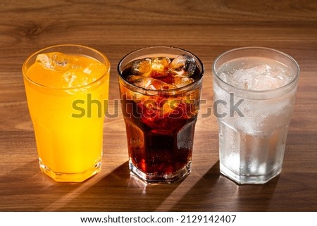 Glasses of soda flavors orange, lemon and coke.