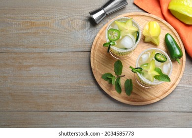 Glasses Of Spicy Cocktail With Jalapeno, Carambola And Mint On Wooden Table, Flat Lay. Space For Text