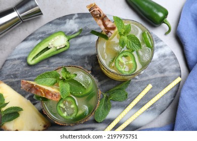 Glasses Of Spicy Pineapple Cocktail With Jalapeno And Mint On Grey Table, Flat Lay