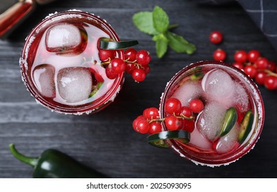 Glasses Of Spicy Red Currant Cocktail With Jalapeno On Black Wooden Table, Flat Lay