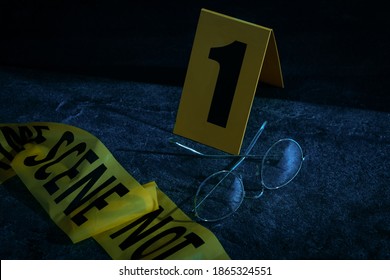 Glasses With Tape And Crime Scene Marker On Stone Table At Night