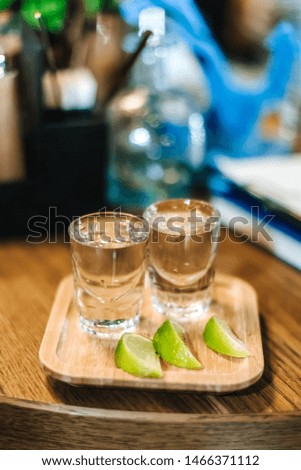 glasses of tequila on a stand with slices of lime on the bar counter