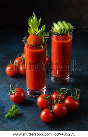 glasses of tomato juice served with  cucumber and celery