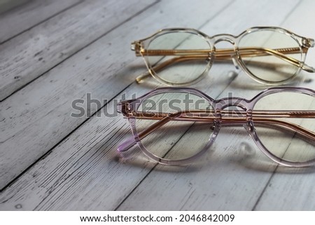 Glasses for vision in a plastic colored frame, with movable nose pads. A pair of panto-shaped eyeglasses lie on a wooden surfacepink. Eyesight accessory. Eyewear shop concept. Optical content