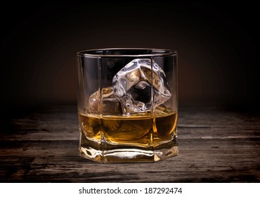 Glasses of whiskey on wood background.