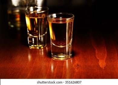 Glasses Of Whiskey Shots On Wooden Surface