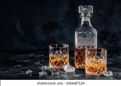 Glasses Of The Whiskey With A Square Decanter On A Black Stone Background.