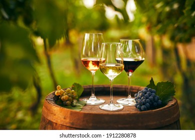 Glasses of white, pink and red wine on an old wooden barrel in the vineyard
 - Shutterstock ID 1912280878