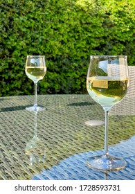 Glasses Of White Wine On The Glass Table Top Of Garden Furniture, No People, Copy Space.