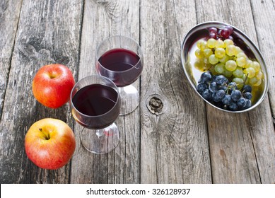 glasses of wine and apples, grapes on old wooden table - Shutterstock ID 326128937