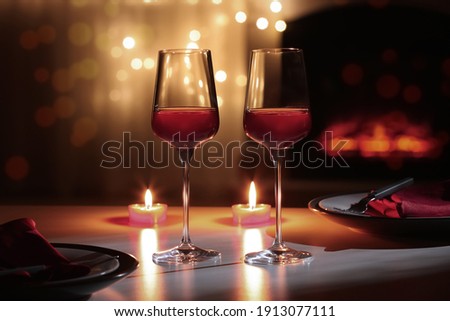 Glasses of wine and candles on table against blurred lights. Romantic dinner