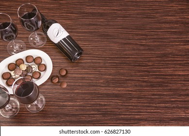 Glasses of wine and chocolates on wooden background