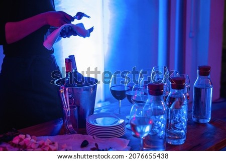 Glasses of wine and snacks on a bar table in night club blue and red neon lights. Party or nightlife entertainment with copy space