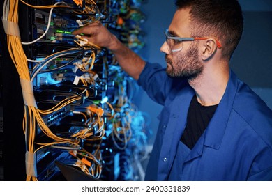 In glasses. Young man is working with internet equipment and wires in server room. - Powered by Shutterstock