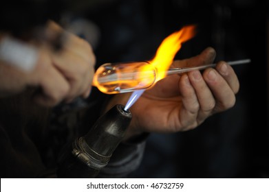 Glass-making with a glass bead-making torch flaming on glass.