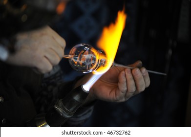 Glass-making with a glass bead-making torch flaming on glass.