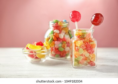 Glassware with different candies and succades on table against color background - Powered by Shutterstock