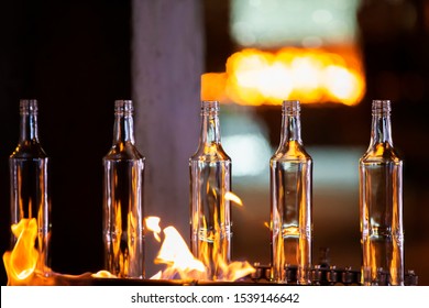 Glassworks. Glass industry. Making glass bottles. Hot bottle blanks in flame - Powered by Shutterstock