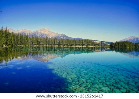 Glassy, transparent blue waters of Lake Beauvert near Jasper in the Canada Rockies