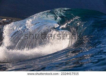 glassy wave breaking on a reef in dark water with a blue sky background