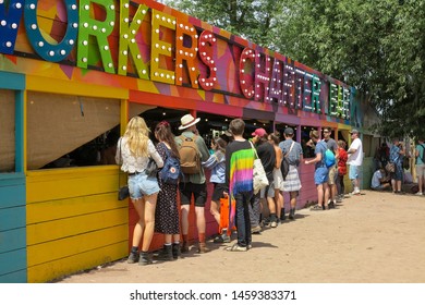 Glastonbury, England - 30 June 2019 - Festival-goers Queue For Drinks At A Rainbow Coloured Bar At Glastonbury 2019.  Image Has Copy Space.