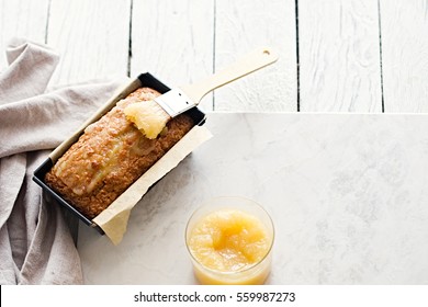 Glazed Applesauce Oatmeal Bread In Baking Pan On A White Marble Table. Ideal Healthy Breakfast With A Hot Coffee And Loaf Cake.