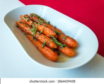 Glazed Carrots With Dill And Thyme On White Tablecloth And Red Table Runner