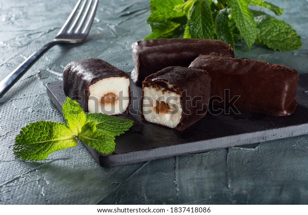Glazed cheese with condensed milk\
on a Board with mint. Cheese on a green background with\
mint.