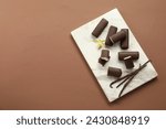 Glazed curd cheese bars, vanilla pods and flower on light brown background, top view. Space for text