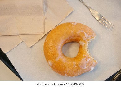 Glazed Donut With A Mouth Bite Mark And Coffee On The Table Was Beautifully Decorated In Store To Service To The People In The Morning.