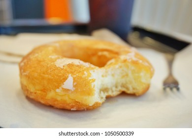 Glazed Donut With A Mouth Bite Mark And Coffee On The Table Was Beautifully Decorated In Store To Service To The People In The Morning.