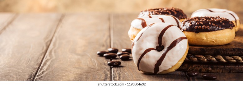Mini ciambelle smaltate con caramelle al caffè su fondo legno. Concetto di cibo per feste con spazio copia. Striscione.